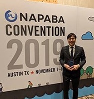 Noree Lee standing in front of a NAPABA Convention Banner