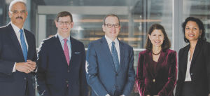 Group photo of five professionals Eric Holder Jr., Steven Fagell, Lanny Breuer, Nancy Kestenbaum, Mythili Raman posing in front of a building