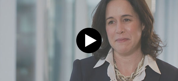 Professional Headshot Still of Marney Cheek talking in front of a window with buildings in the background