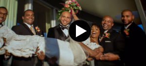 Five individuals in tuxes carrying a bride in a wedding dress holding flowers